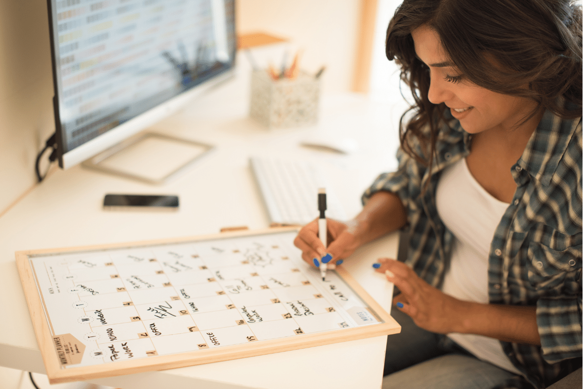 A woman diligently writes on a board with a pen, focused on her task and surrounded by a professional environment.